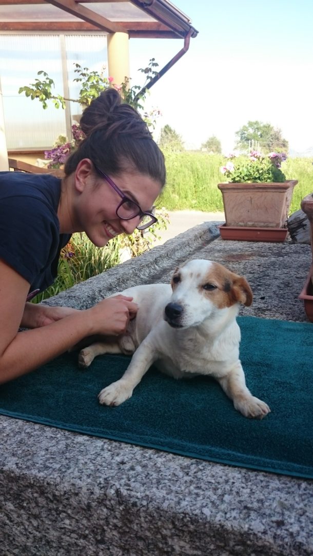 Malika Bolle, co-directrice, souriante, la main posée sur un petit chien blanc et roux allongé sur une serviette